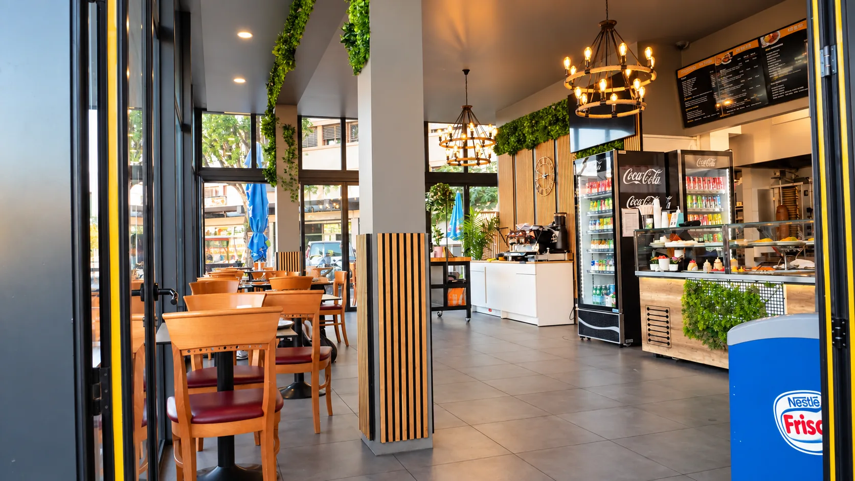 Intérieur de Tamaris Food à Lancy : tables et chaises en bois, comptoir et vitrine réfrigérée